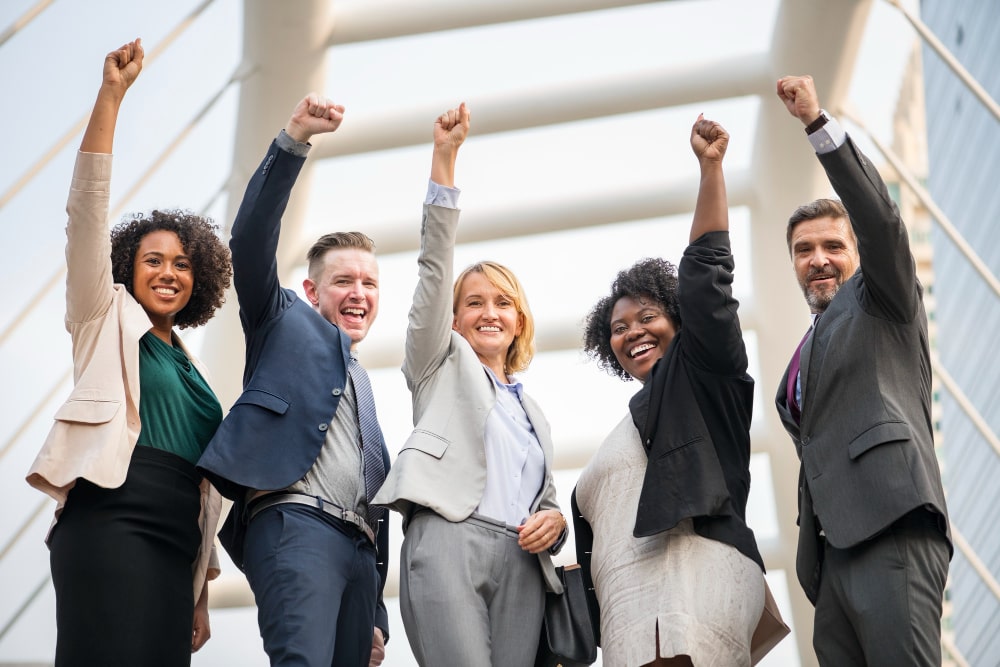 Diverse group of business leaders raising their arms in celebration, representing TalentIQ Ireland’s executive search services connecting organizations with transformative leadership talent.